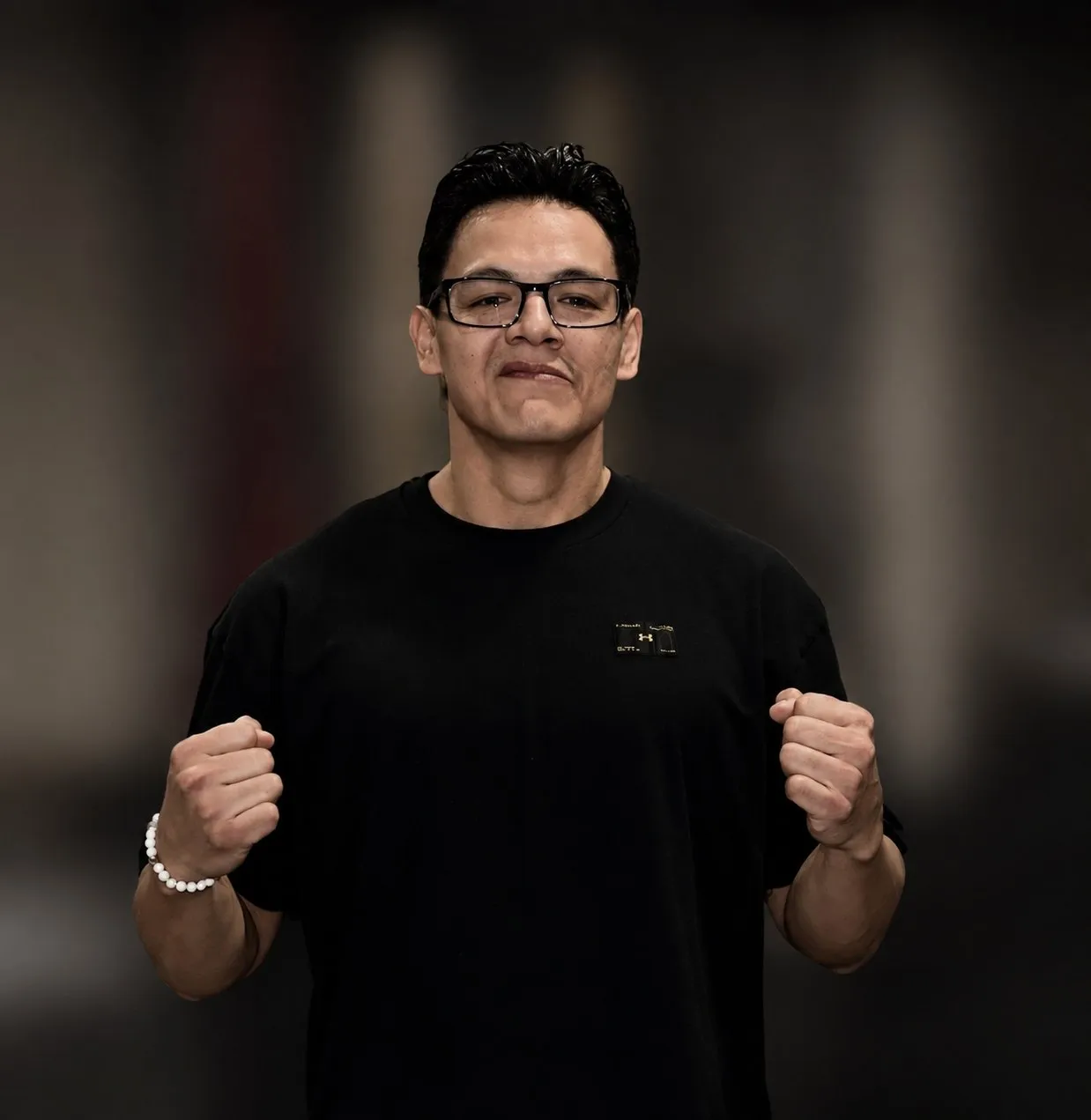 Head Coach Adam Toto in the gym with his fists raised.